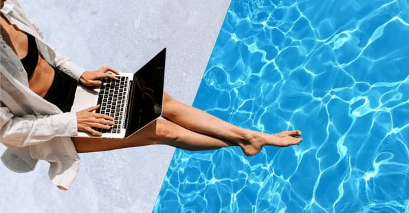 A woman from the neck down with a laptop on her lap wearing a black bathing suit and a white button-down shirt.